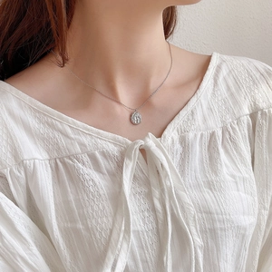 Silver necklace with textured round pendant worn by a model on a delicate chain
