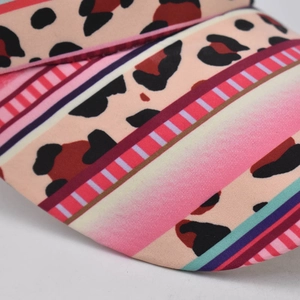 Macro shot of baseball cap brim featuring leopard print and colorful striped canvas fabric