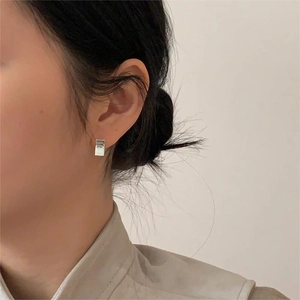 Minimalist rectangular silver stud earrings with high polished finish on model's ear