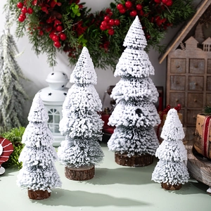 Miniature cedar Christmas trees with flocking snow and wooden bases in a cozy winter scene