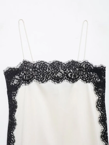 Detail of white satin camisole featuring delicate black lace trim and slender straps