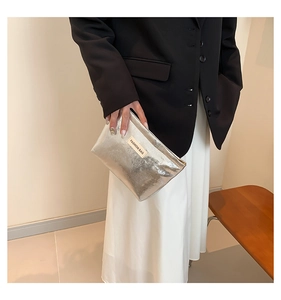 Detail of silver metallic fashion bag held by model featuring chic textured finish