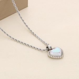 Detail of silver heart pendant necklace with central white bead and beaded edge decoration