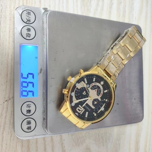 Detailed shot of a gold-tone business watch on a digital scale weighing 56.6 grams