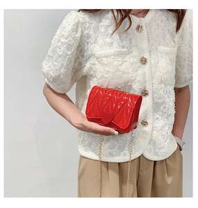 Detail of red heart buckle and V-shaped pleated texture on mini chain crossbody bag
