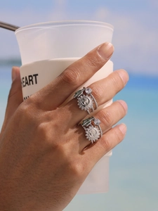 Detail of stacked silver sun rings with green and white zircons worn on hand