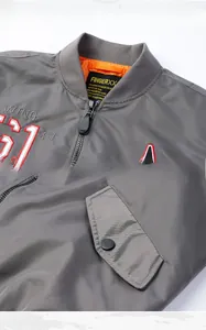 Detail show of grey bomber jacket with orange lining, embroidery and metal snap pocket