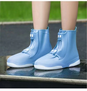 Detail of light blue waterproof silicone shoe covers with button closure and white non-slip sole