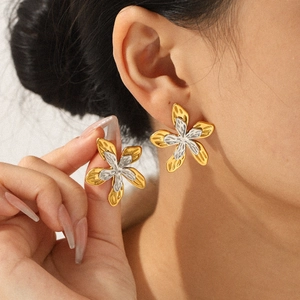 Two-tone gold and silver hammered metal flower earrings worn by a model in a close-up view
