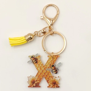 Detail of honey bee letter K acrylic keychain with golden clasp and yellow leather tassel