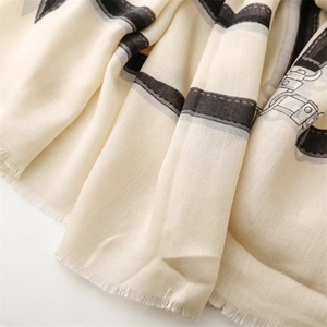 Close-up of beige linen-feel scarf featuring grey belt patterns and soft fringe edges