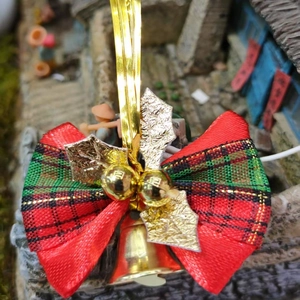 Close-up of a red and green plaid Christmas bow with golden bells and leaf ornaments
