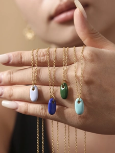 Nahaufnahme bunter Emaille-Anhänger mit minimalistischen 18k vergoldeten Ketten