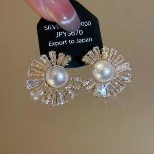 Macro shot of gold plated sunflower pearl earrings with sparkling cubic zirconia stones