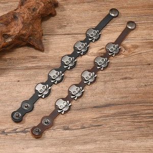 Detail of vintage skull leather bracelets in black and brown on a wooden background