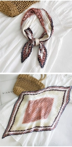 Dettaglio di un foulard di seta plissettato con motivi geometrici rosa su borsa in paglia