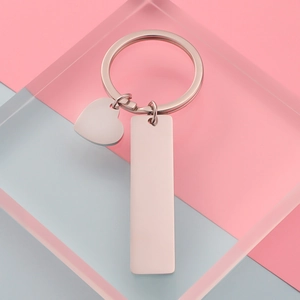 Polished rose gold keychain with heart and rectangular charms on a creative background