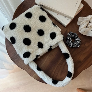 Vue détaillée du sac à main en peluche à pois sur table en bois avec décor cosy