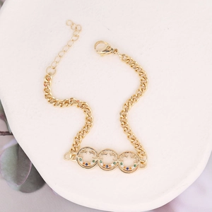 Close-up of gold chain bracelet with multicolor zircon inlays on a white tray