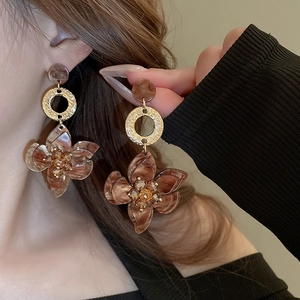 Detail of retro acetate flower earrings with marble texture and golden metal accents