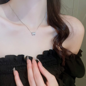Polished silver H-letter pendant necklace with zircon on elegant female neck