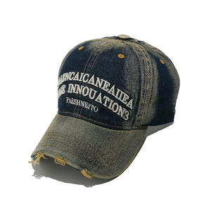 Dettaglio cappello baseball in denim vintage con ricamo bianco e tesa effetto strappato