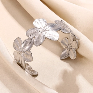 Brushed silver floral cuff bracelet featuring five large blooming flowers on satin background