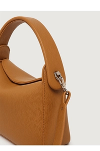 Close-up of caramel lychee grain leather texture and silver hardware on a handbag