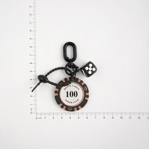 Monte Carlo poker chip and black dice keychain size measurement on a ruler