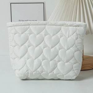 Close-up of white quilted heart pattern on large cosmetic bag with soft lifestyle lighting