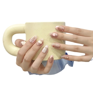 Faux ongles roses faits main avec motifs de cœur 3D et nœud sur une tasse en céramique