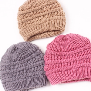 Three warm knit beanie hats in camel, gray and rose pink colors with ribbed texture