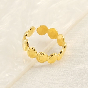 Detail of adjustable gold shell ring on elegant white fabric with water texture