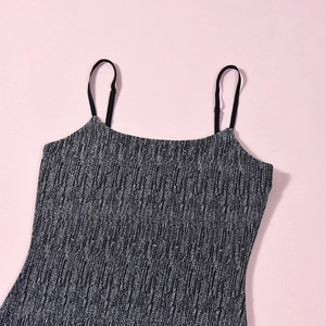Détail de la texture pailletée argentée et des fines bretelles de la robe noire