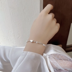 Elegant S925 silver heart bracelet with white pearls on a female wrist with lace sleeve