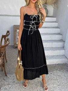 Detail of black A-line dress with white lace bows and wavy hem in vacation setting