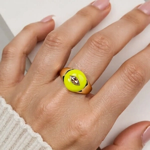 Detail of model wearing a wide gold heart ring with green enamel and brown zircon