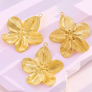 Detailed macro view of three vintage gold stainless steel flower charms for DIY jewelry making