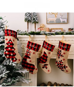 Detail of four red and black plaid burlap Christmas stockings hanging on a white mantel