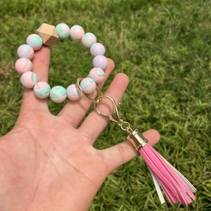 Hand holding a colorful silicone bead keychain with floral patterns and a pink tassel