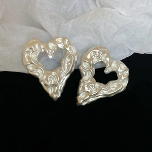Detail view of irregular molten texture on champagne gold hollow heart earrings