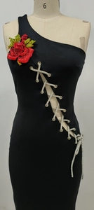 Détail de fleur en strass rouge et laçage en cristal sur une robe noire asymétrique
