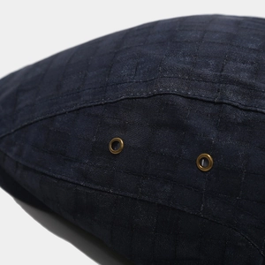 Detailed close-up of navy blue grid fabric with bronze eyelets on a retro newsboy cap