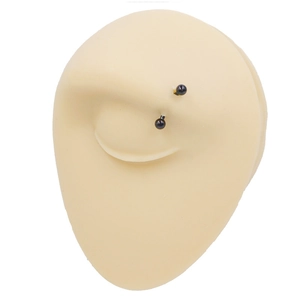 Macro shot of flesh-toned silicone eyebrow piercing model with a curved black barbell