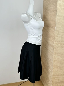 Side view of white tank top paired with a black pleated skirt on a mannequin