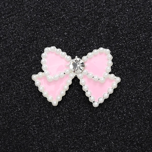 Macro detail of pink bow charm with pearl border and sparkling center rhinestone