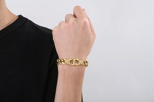 Close-up of a chunky gold stainless steel curb chain bracelet worn by a male model