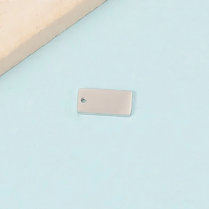 Macro detail of rectangle stainless steel pendant tags on blue background with stone