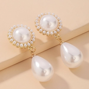 Vue macro de boucles d'oreilles dorées avec perles blanches et pendentif goutte