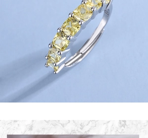 Close-up of square yellow zircon gemstones set in a silver-toned wide band ring